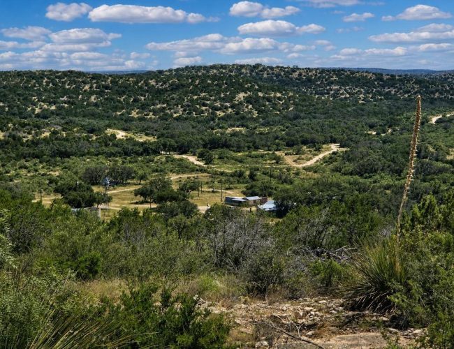 3E Ranch hilltop view over wooded valley to headquarters buildings, Edwards County, Texas