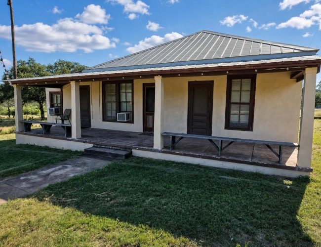 3E Ranch stucco house front porch with wooden benches and window air conditioners