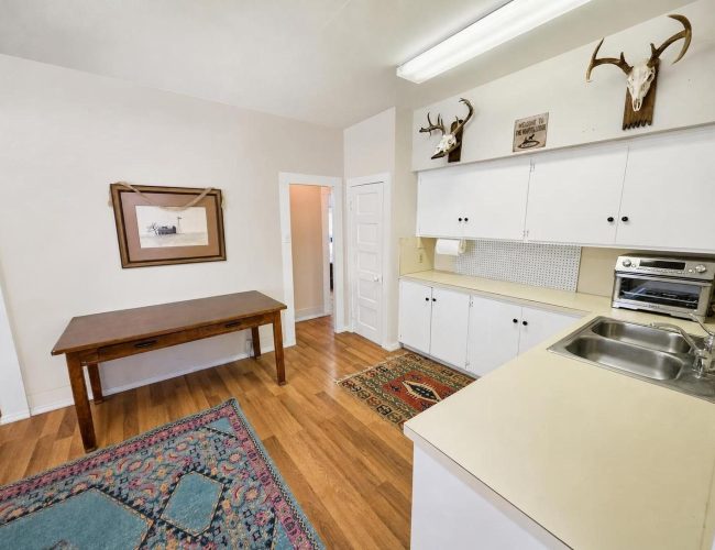 3E Ranch kitchen with white cabinets, double sink, and wooden table