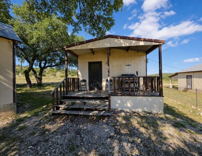 3E Ranch small building with covered wood deck and grill under an oak