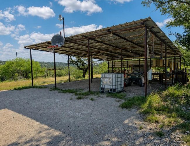 3E Ranch open carport with basketball hoop, water tote, and ranch equipment