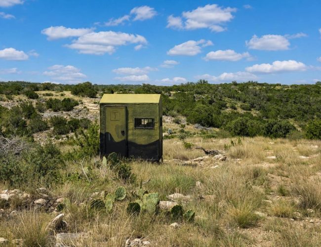 3E Ranch green hunting blind on rocky hillside with prickly pear