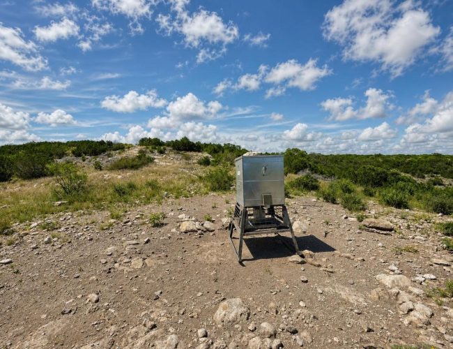 3E Ranch galvanized feeder on metal stand in rocky clearing